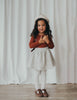 US stockist of Karibou Kid's Coco Linen Suspender Skirt in the Frosted Cherry Edition.  Features natural linen skirt with contrasting mauve suspender straps and bows on back.