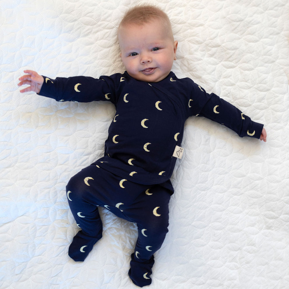 Stockist of Bonsie Babywear's Footed, dark blue "Gnight Moon" kimono style romper featuring a crescent moon print