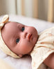 US stockist of Minikane's Yaelle Bambini doll dressed in her Helene Clara romper, matching headband and cream sandals.