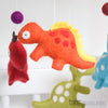 Colorful dinosaur mobile with hanging pom-poms against a light blue background.  US stockist of Tara Treasures.