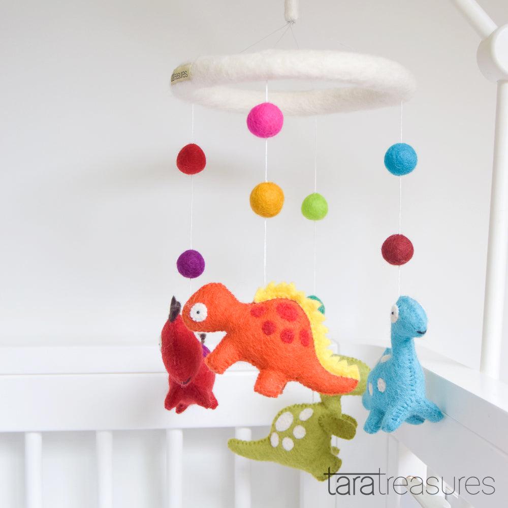 Colorful dinosaur mobile with hanging pom-poms against a light blue background.  US stockist of Tara Treasures.