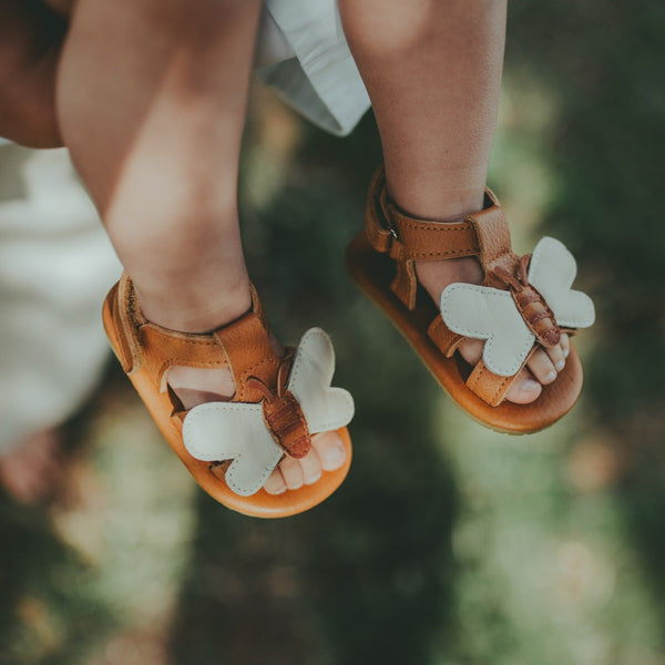 US stockist of Donsje USA's Honey Bee Tuti Sky  premium handmade leather sandals.  Tan in color with beautiful tan/cream honey bee on front and velcro fastening at back.  Sizes 0-12 mths have soft sole, 12-30mths have a soft flexible, rubber sole.