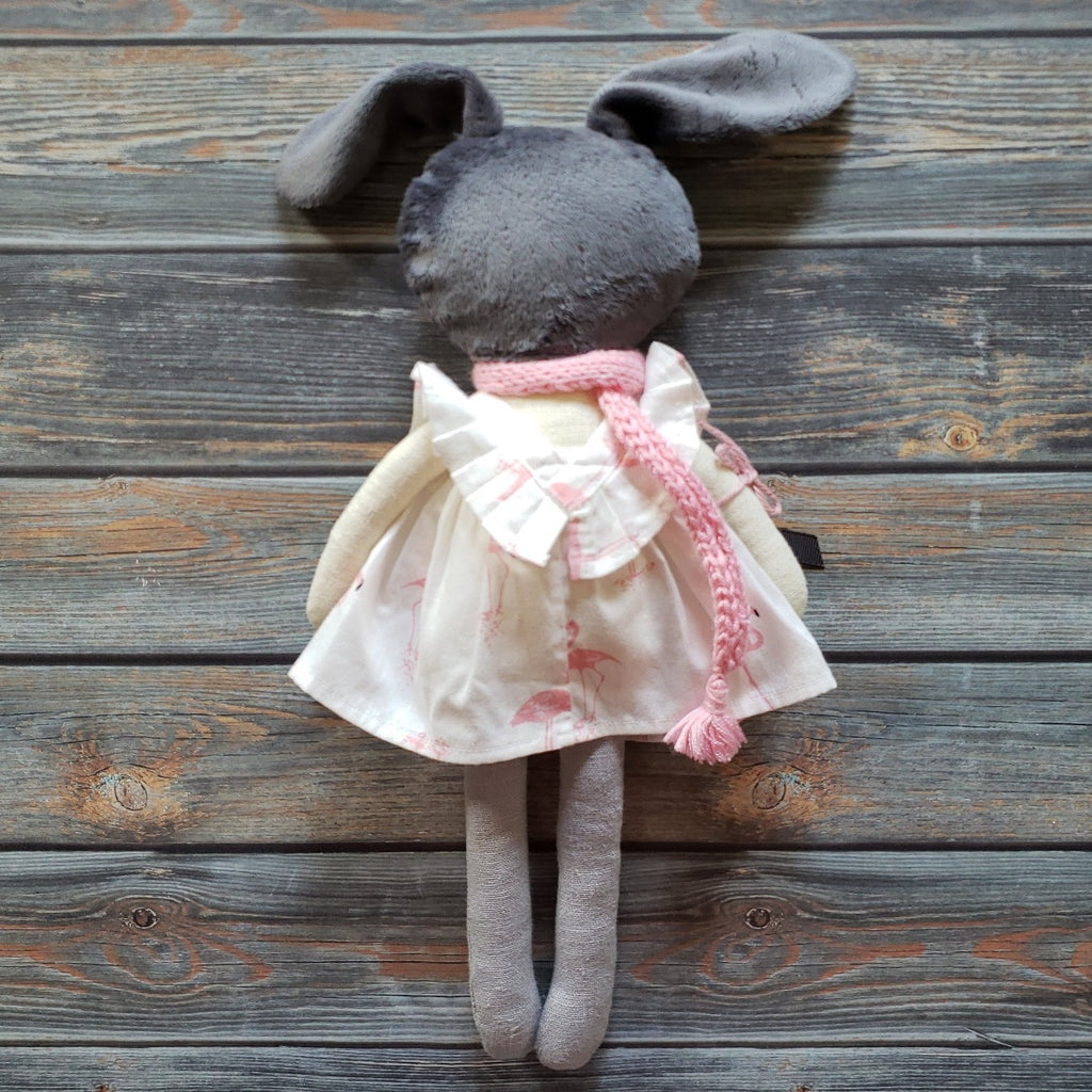 US stockist of Vasya Vasya's heirloom quality girl bunny made from linen fabric, soft plush and hypoallergenic filler.  Cream color with grey head and ears.  Wears beautiful flamingo print dress with pink scarf.  Measures approximately 15".