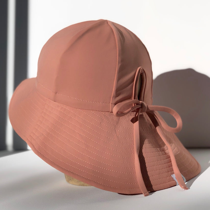 US stockist of Fini the Label's gender neutral, floppy swim hat in cocoa. Features elongated back for added sun protection, chin strap and adjustable bow around crown for better fit. Brim is medium stiffness and can be flipped up at front.  Made from nylon/spandex and is quick drying.