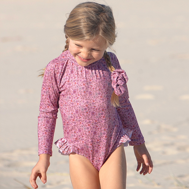 US stockist of Salty Swimwear's Zoe long sleeve rashsuit in candy wildflowers.  Made from pink UPF 50+ recycled Repreve fabric with pretty wildflower print. Fully lined, with invisible back zipper and signature Salty frill on legs.