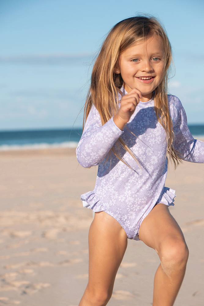 US stockist of Salty Swimwear's Zoe long sleeve rashsuit in Purple daisy days.  Made from purple UPF 50+ recycled Repreve fabric with pretty white daisy print. Fully lined, with invisible back zipper and signature Salty frill on legs.