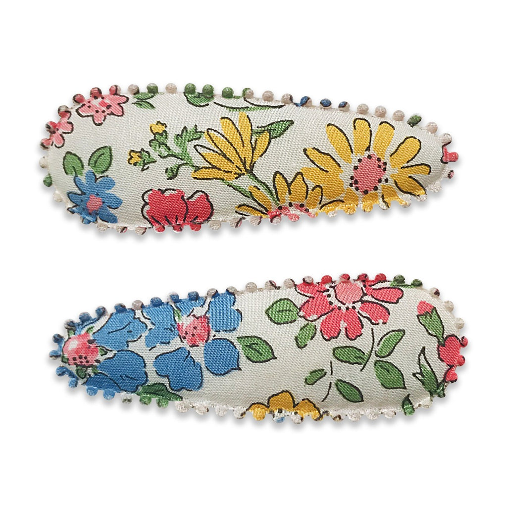 US stockist of Josie Joan's Ava fabric hair clips.  Set of two on pale fabric with beautiful yellow, blue, pink or red flowers and contrasing green leaves.  Has scalloped edges.