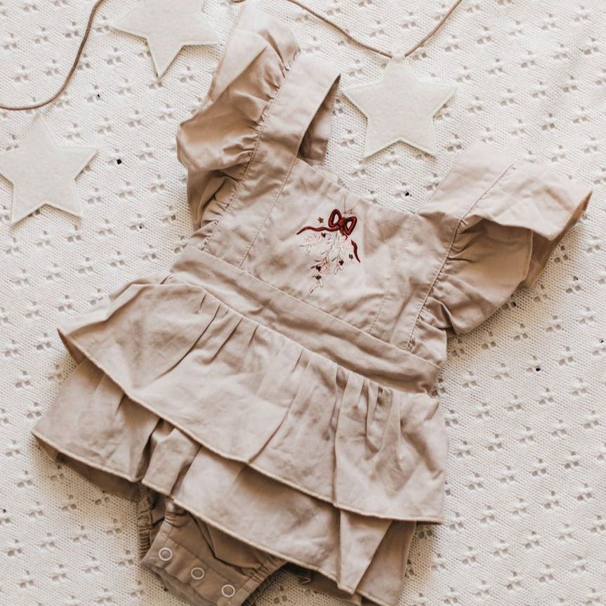 US stockist of Bencer & Hazelnut's Christmas Fir Playsuit.  Made from oatmeal colored cotton fabric, with ruffles on the back and embroidery on the front.  Snaps at crotch.