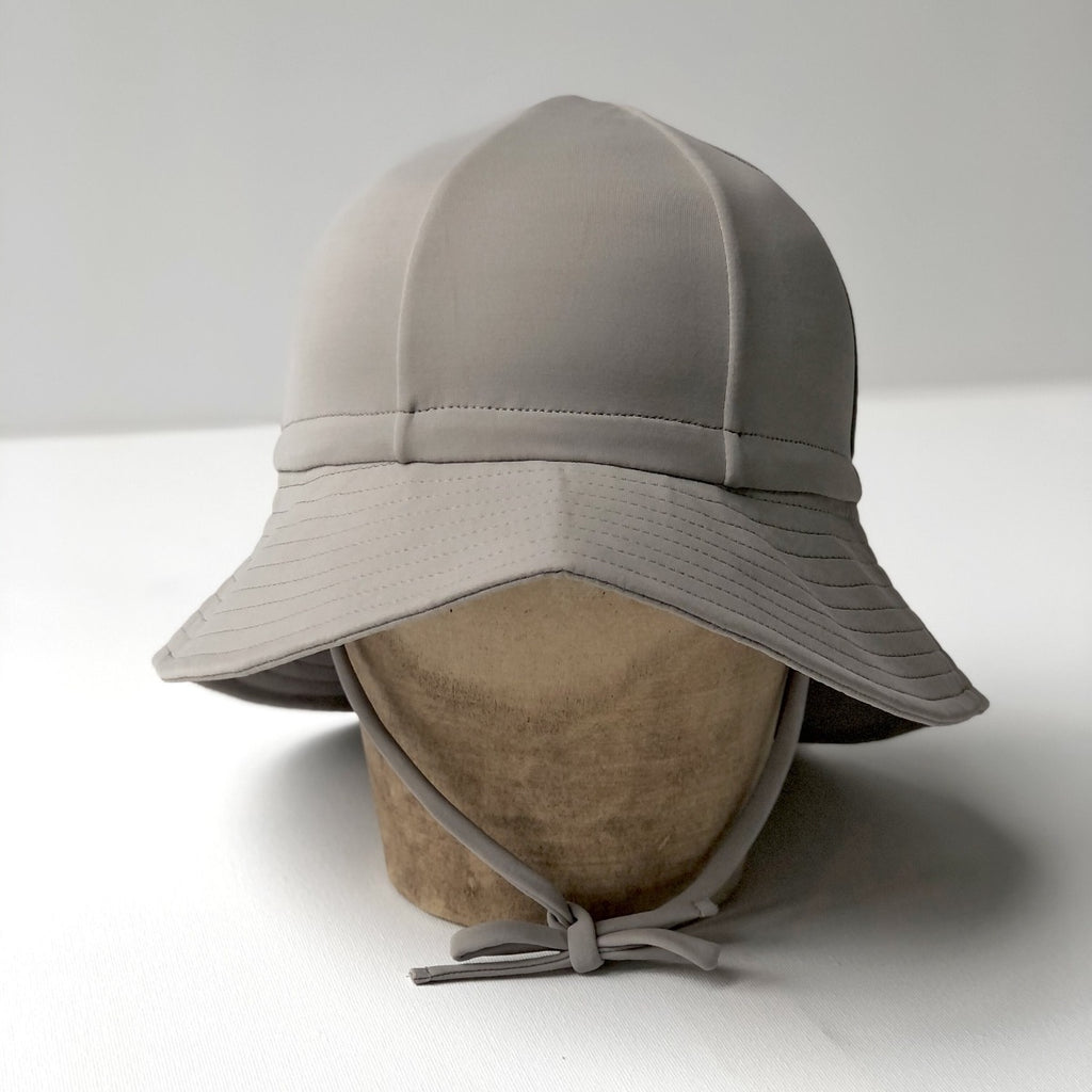 US stockist of Fini the Label's gender neutral, floppy swim hat in mushroom. Features elongated back for added sun protection, chin strap and adjustable bow around crown for better fit. Brim is medium stiffness and can be flipped up at front.  Made from nylon/spandex and is quick drying.