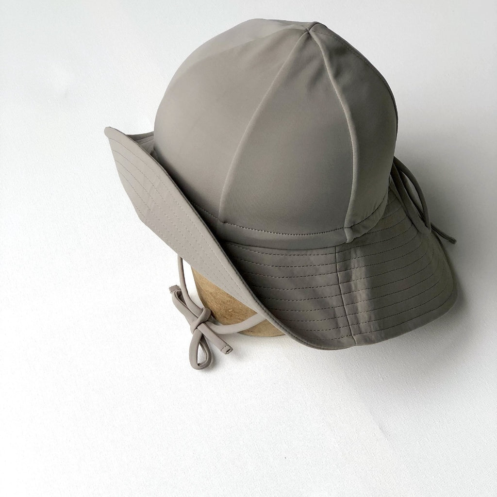 US stockist of Fini the Label's gender neutral, floppy swim hat in mushroom. Features elongated back for added sun protection, chin strap and adjustable bow around crown for better fit. Brim is medium stiffness and can be flipped up at front.  Made from nylon/spandex and is quick drying.