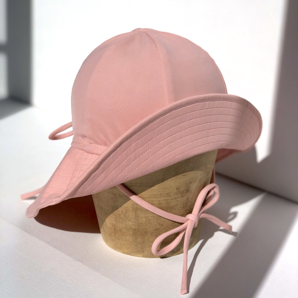US stockist of Fini the Label's floppy swim hat in pink. Features elongated back for added sun protection, chin strap and adjustable bow around crown for better fit. Brim is medium stiffness and can be flipped up at front.  Made from nylon/spandex and is quick drying.