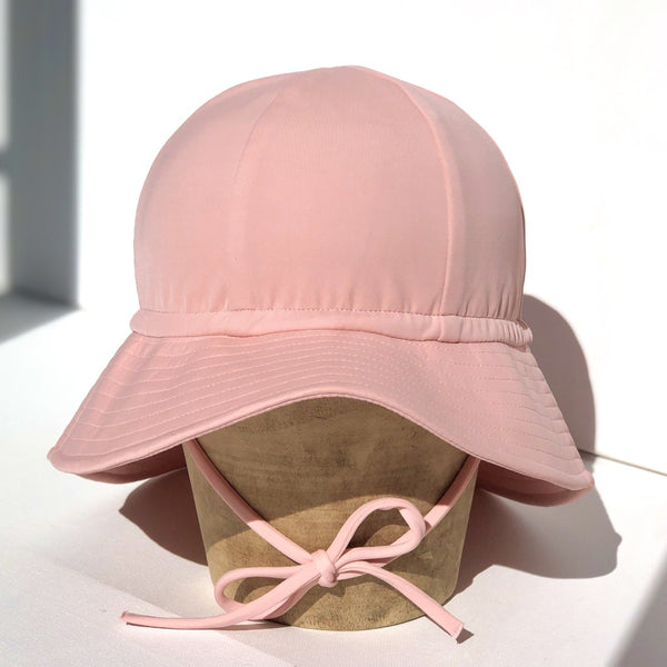 US stockist of Fini the Label's floppy swim hat in pink. Features elongated back for added sun protection, chin strap and adjustable bow around crown for better fit. Brim is medium stiffness and can be flipped up at front.  Made from nylon/spandex and is quick drying.