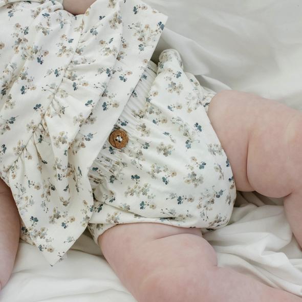US stockist of Buck & Baa's organic cotton floral bloomers.  Made from cream fabric with blue floral print. Features coconut button on front and elastic waist.
