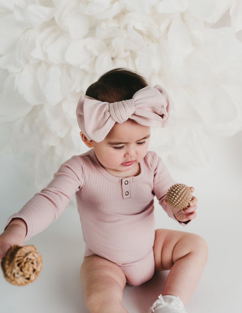 US stockist of Karibou Kids soft pink Willow long sleeve henley bodysuit in ribbed cotton blend.