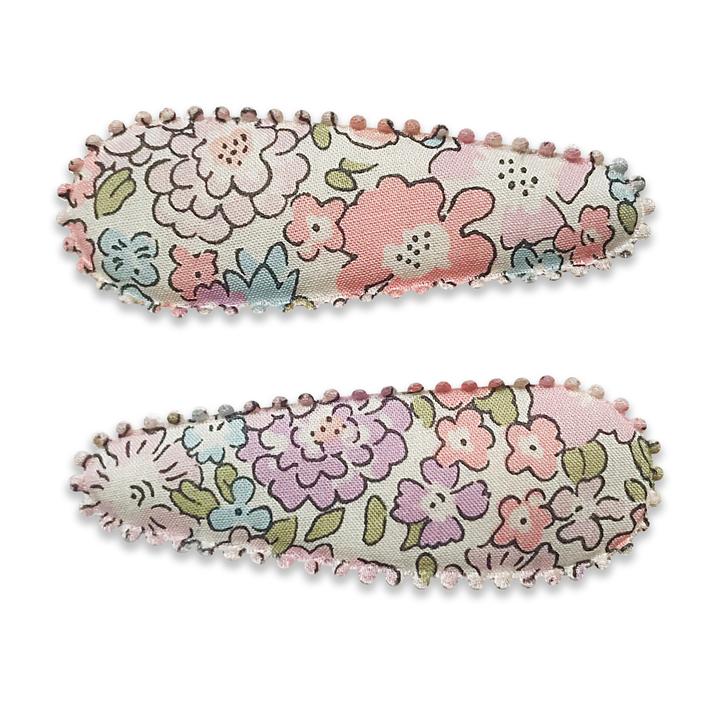 US stockist of Josie Joan's Lillia set of two fabric hair clips.  Cream colored fabric with pastel flowers in hues of pink, purple, blue and with green foilage. Features scalloped edges.