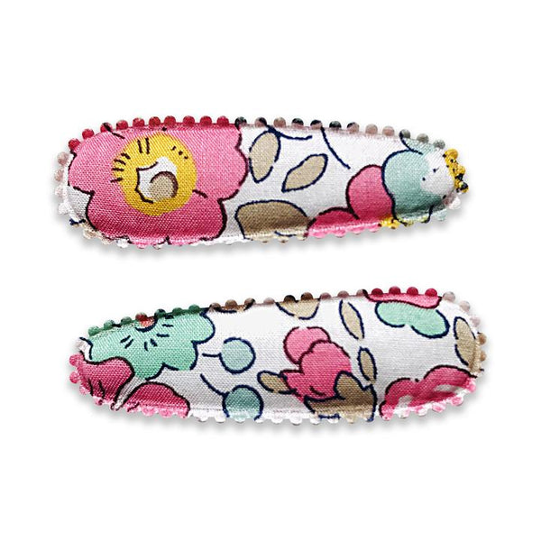 US stockist of Josie Joan's Little Poppy fabric hair clips.  Set of two fabric baby hair clips made from pale coloured fabric with blue and pink flowers and  contrasting tan leaves.  Has scalloped edging.