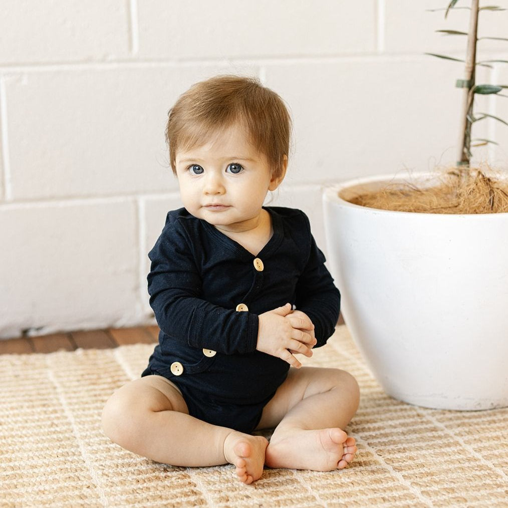 US stockist of Two Darling's long sleeve bamboo/cotton midnight blue bodysuit. Kimono style crossover front with four functioning wooden buttons.  Snaps at crotch.