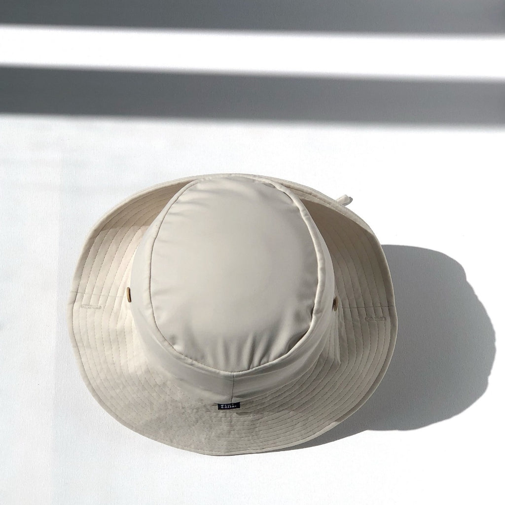 US stockist of Fini the Label's gender neutral, sailor swim hat in cream. Features elongated back for added sun protection, wide brim and chin strap. Brim is medium stiffness and can be flipped up at front. Sides can be worn buttoned up for that sailor look.  Made from nylon/spandex and is quick drying.