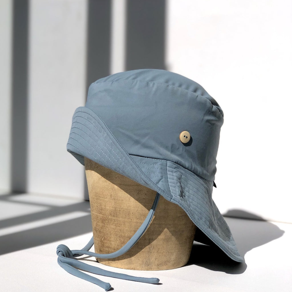 US stockist of Fini the Label's gender neutral, sailor swim hat in heaven. Features elongated back for added sun protection, wide brim and chin strap. Brim is medium stiffness and can be flipped up at front. Sides can be worn buttoned up for that sailor look.  Made from nylon/spandex and is quick drying.