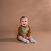 US stockist of Grown Clothing's gender neutral, speckled stone romper.  Made from extra fine Australian merino wool. Features pearl knit detail at edges, adjustable straps and wooden buttons.