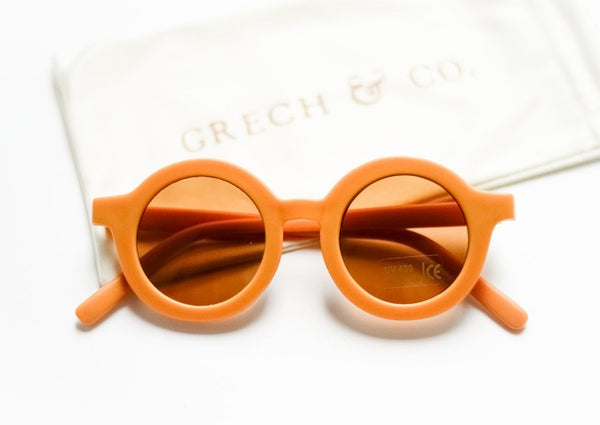 US stockist of Grech & Co's gender neutral sustainable sunglasses.  Made from recycled plastic, with round amber lens with UV 400 protection in a golden color.