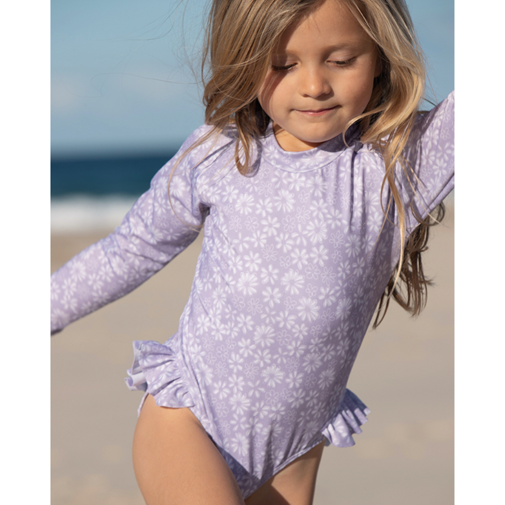 US stockist of Salty Swimwear's Zoe long sleeve rashsuit in Purple daisy days.  Made from purple UPF 50+ recycled Repreve fabric with pretty white daisy print. Fully lined, with invisible back zipper and signature Salty frill on legs.