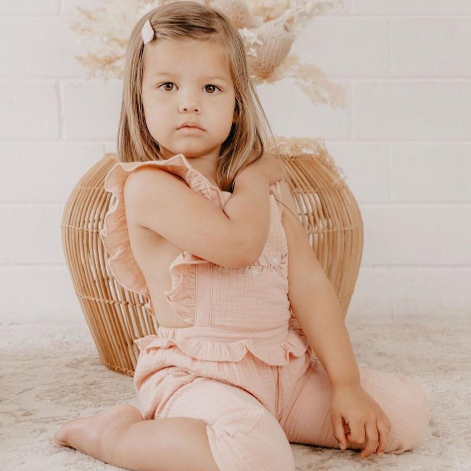 US stockist of India and Grace the Label's vintage pink embroidered ruffle jumpsuit.  Features ruffle straps that cross over the back, floral embroidery on the chest, ruffle at waist and 3/4 legs.  Made from double cotton gauze.