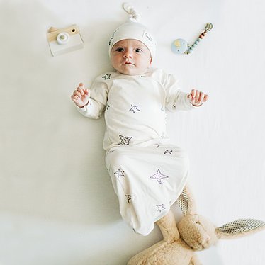 Stockist of Bonsie's rayon blend baby gown in gender neutral white fabric with star print.  Features cross over velcro top that can be undone for skin to skin.  Elastic waist which can be pulled down for easy diaper changes.
