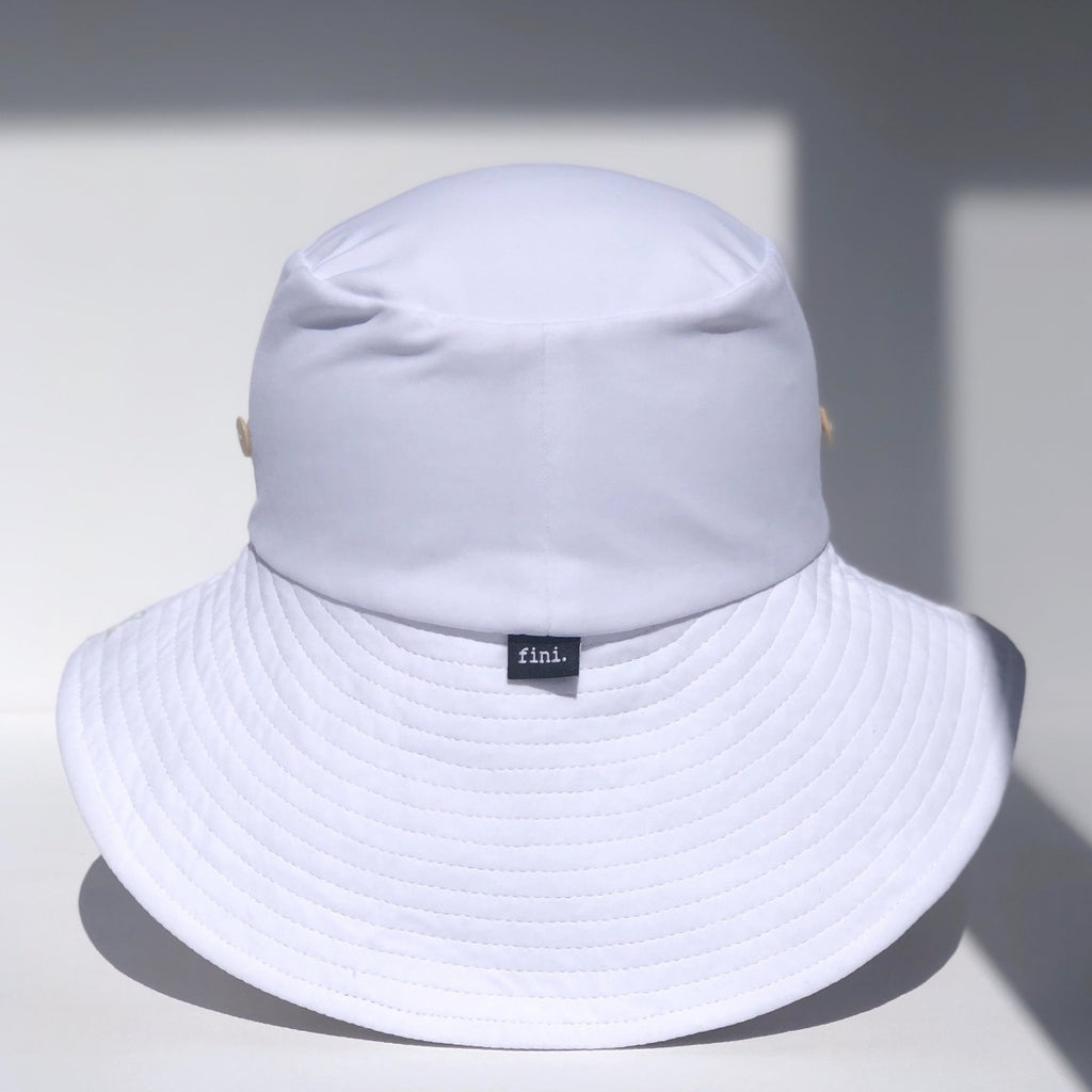 US stockist of Fini the Label's gender neutral, sailor swim hat in white. Features elongated back for added sun protection, wide brim and chin strap. Brim is medium stiffness and can be flipped up at front. Sides can be worn buttoned up for that sailor look.  Made from nylon/spandex and is quick drying.