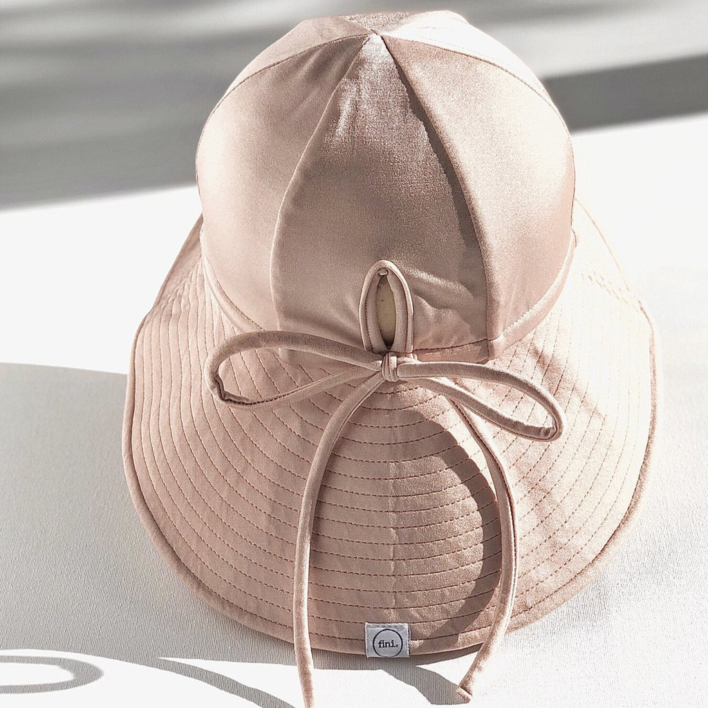 US stockist of Fini the Label's gender neutral, floppy swim hat in Shimmer Champagne. Features elongated back for added sun protection, chin strap and adjustable bow around crown for better fit. Brim is medium stiffness and can be flipped up at front.  Made from nylon/spandex and is quick drying.