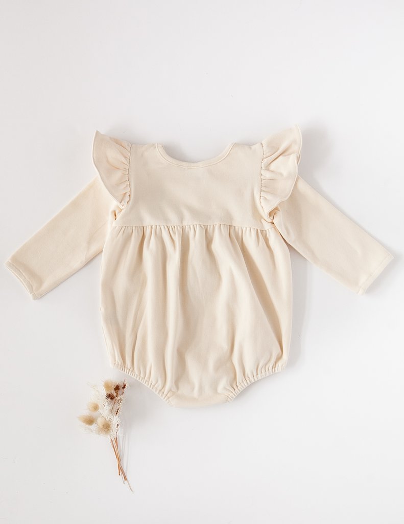 US stockist of Karibou Kid's Milana Winged Playsuit in almond cream.  Made from soft cotton, featuring long sleeves and ruffled wings at shoulders.