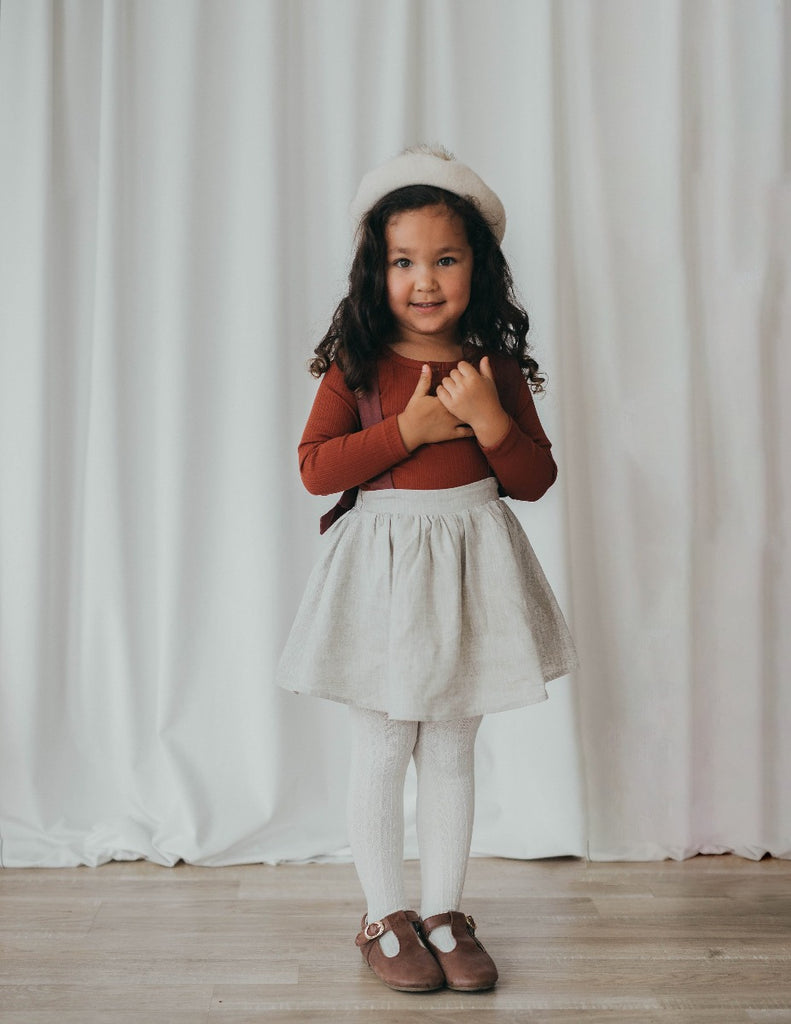 US stockist of Karibou Kid's Coco Linen Suspender Skirt in the Frosted Cherry Edition.  Features natural linen skirt with contrasting mauve suspender straps and bows on back.