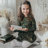 US stockist of Karibou Kids' Royal Visit Long Sleeve Pocket Dress in Emerald.  Made from cotton in a rich emerald green color with contrasting gold swirl print and ties at neck.
