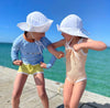 US stockist of Fini the Label's gender neutral floppy swim hat in white. Features elongated back for added sun protection, chin strap and adjustable bow around crown for better fit. Brim is medium stiffness and can be flipped up at front.  Made from nylon/spandex and is quick drying.